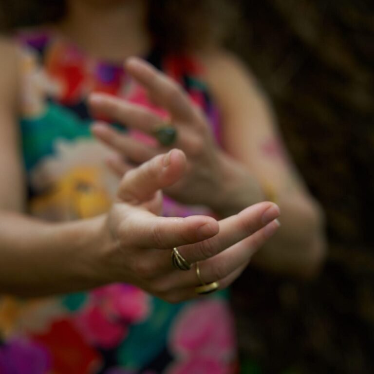 Manos de una persona con anillos, extendidas hacia adelante, con un fondo desenfocado.