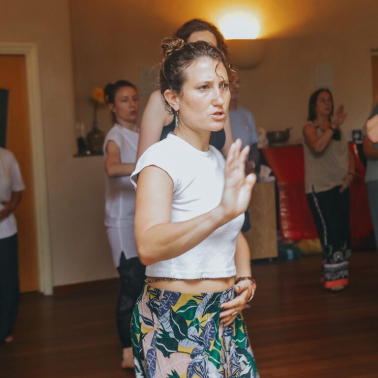 Grupo de personas participando en una clase de movimiento en un espacio interior.